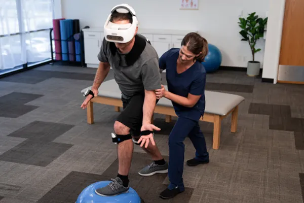 Physical therapist stabilizes client wearing the REAL System VR headset